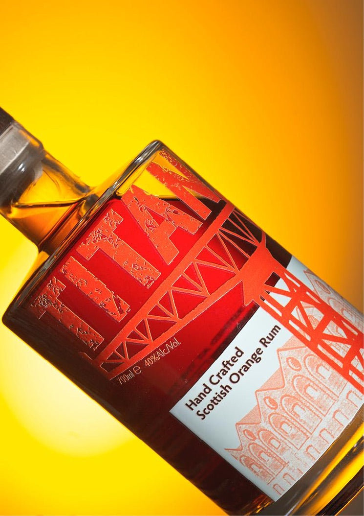 Bottle of Titan Hand Crafted Scottish Orange Rum with a Gold Rum Award badge on a yellow background,