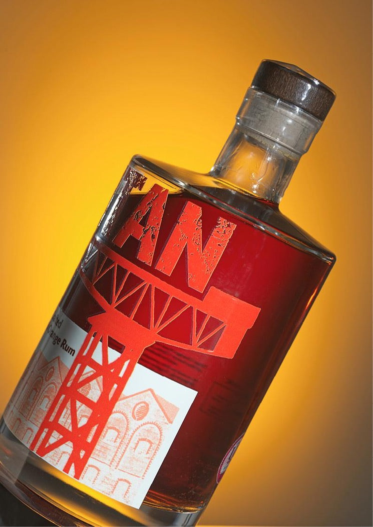 Bottle of Titan Hand Crafted Scottish Orange Rum with a Gold Rum Award badge on a yellow background,